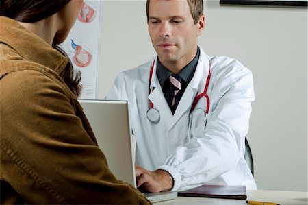 Médecin sur ordinateur portable avec le patient au bureau Photographie de stock - Premium Libres de Droits, Code: 644-03659661