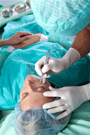 Surgeon with scalpel to patient's face Foto de stock - Sin royalties Premium, Código: 644-03672111