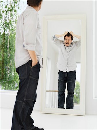 reflection in a mirror - Man examining his grimacing reflection Stock Photo - Premium Royalty-Free, Code: 649-04247756