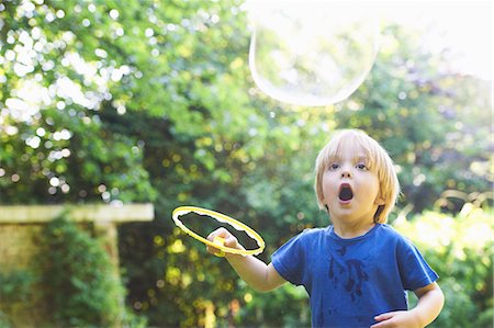 float boy - Boy making oversized bubble in backyard Stock Photo - Premium Royalty-Free, Code: 649-04247854