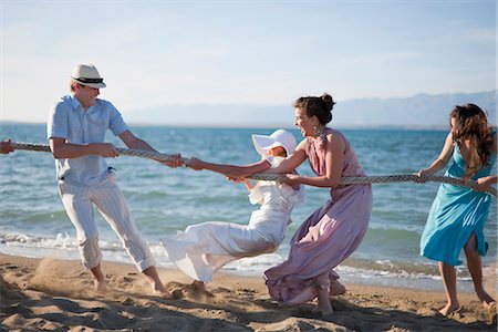 friends together laughing on the beach - Newlyweds and guests playing tug of war Stock Photo - Premium Royalty-Free, Code: 649-04248555