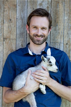 portrait farmer not backlit not flare - Man holding kid goat outdoors Stock Photo - Premium Royalty-Free, Code: 649-04827418