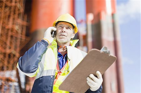 Worker talking on cell phone on oil rig Stock Photo - Premium Royalty-Free, Code: 649-04827674