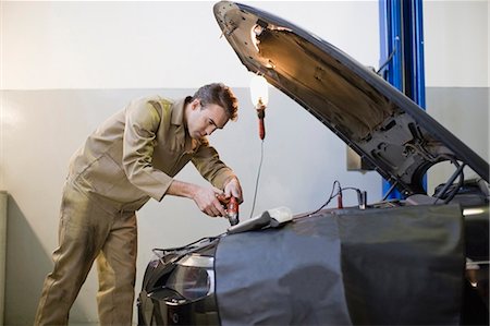 people working in car industry - Mechanic working on car engine in garage Stock Photo - Premium Royalty-Free, Code: 649-05521237