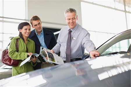 Salesman showing off car in showroom Stock Photo - Premium Royalty-Free, Code: 649-05521296