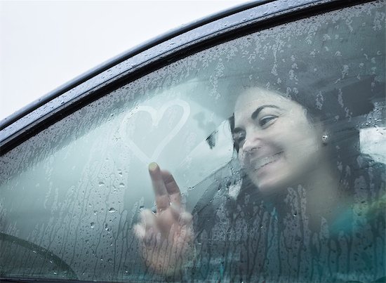 Teenage girl drawing on wet car window Stock Photo - Premium Royalty-Free, Image code: 649-05521540