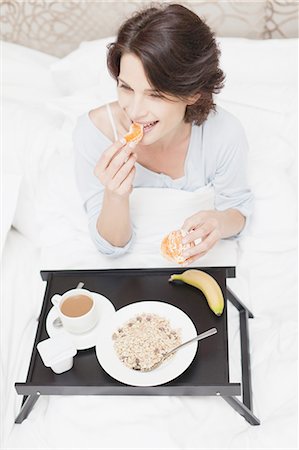 Smiling woman having breakfast in bed Stock Photo - Premium Royalty-Free, Code: 649-05521570