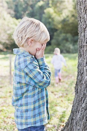 standing girl side view - Children playing hide and seek outdoors Stock Photo - Premium Royalty-Free, Code: 649-05521665
