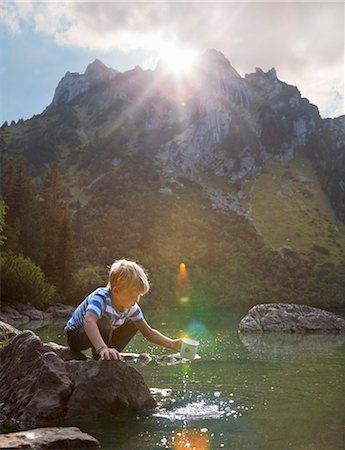 drinking in mountain - Boy dipping mug into still lake Stock Photo - Premium Royalty-Free, Code: 649-05556032