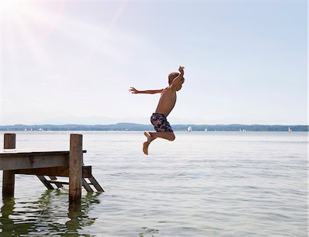Boy jumping into lake from dock Foto de stock - Sin royalties Premium, Código: 649-05556067