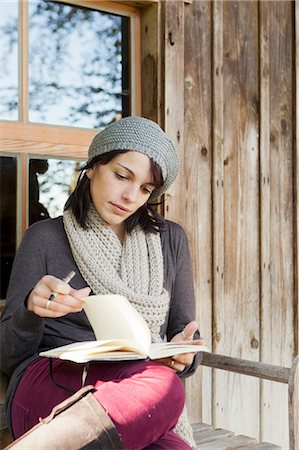 Woman writing in notebook on porch Stock Photo - Premium Royalty-Free, Code: 649-05649619