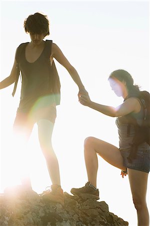 friends back lit - Hikers helping each other climb rock Stock Photo - Premium Royalty-Free, Code: 649-05656874