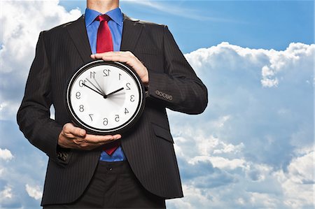 reversal - Businessman holding backwards clock Stock Photo - Premium Royalty-Free, Code: 649-05657045