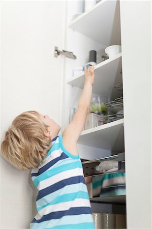 storage (home storage) - Boy reading for something in cabinet Stock Photo - Premium Royalty-Free, Code: 649-05657173