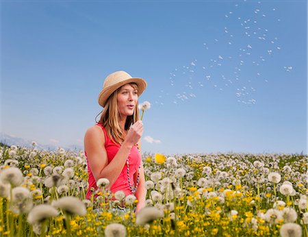 simsearch:6113-06498439,k - Woman blowing dandelions outdoors Foto de stock - Royalty Free Premium, Número: 649-05657674