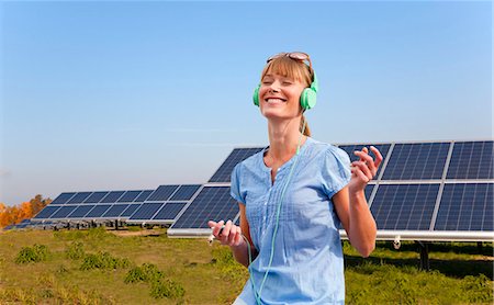 environmental issues and alternative energy - Woman with headphones and solar panels Stock Photo - Premium Royalty-Free, Code: 649-05657719