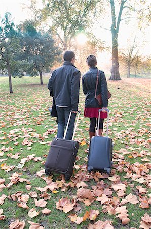 Couple rolling luggage in park Stock Photo - Premium Royalty-Free, Code: 649-05658275