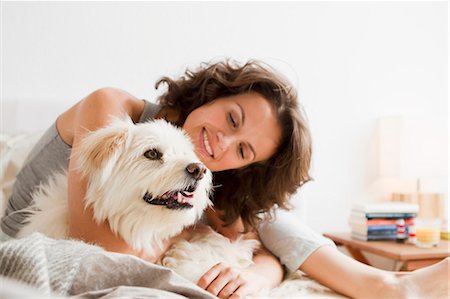 dog happy - Smiling woman petting dog in bed Stock Photo - Premium Royalty-Free, Code: 649-05800977