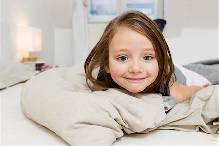 Smiling girl laying on bed Stock Photo - Premium Royalty-Free, Code: 649-05801012
