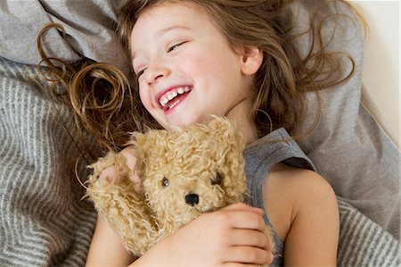 relaxing with kid - Smiling girl holding teddy bear in bed Stock Photo - Premium Royalty-Free, Code: 649-05801020