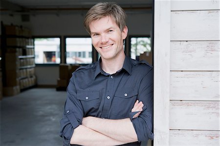 Homme souriant, debout dans le garage Photographie de stock - Premium Libres de Droits, Code: 649-05801086