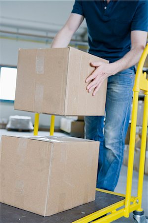 shipping industry - Man stacking cardboard boxes on dolly Stock Photo - Premium Royalty-Free, Code: 649-05801083