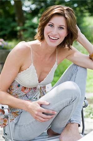 Smiling woman sitting outdoors Stock Photo - Premium Royalty-Free, Code: 649-05801142