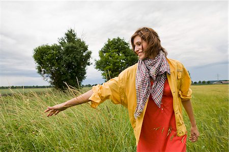 Smiling woman walking in tall grass Stock Photo - Premium Royalty-Free, Code: 649-05801208