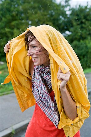 Smiling woman covering hair in rain Stock Photo - Premium Royalty-Free, Code: 649-05801213