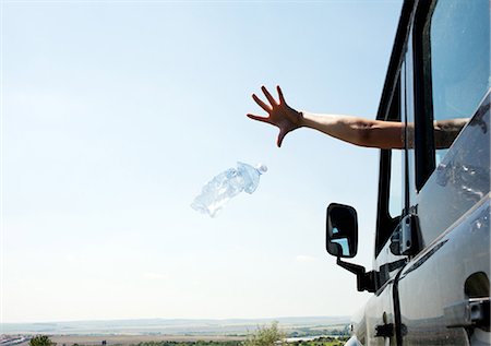 Woman throwing bottle out car window Stock Photo - Premium Royalty-Free, Code: 649-05801242