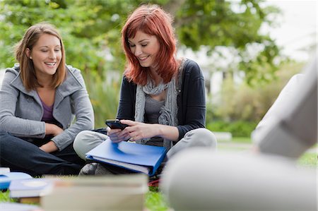 Students using cell phone on grass Stock Photo - Premium Royalty-Free, Code: 649-05801381