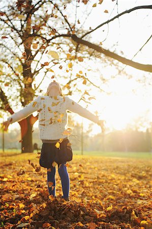 Smiling girl playing in autumn leaves Stock Photo - Premium Royalty-Free, Code: 649-05801615