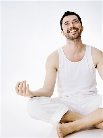 Man in underwear sitting indian style on floor with hands hovering