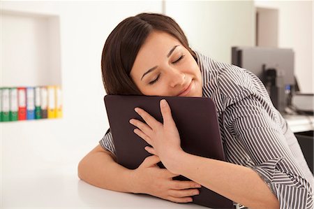 Businesswoman hugging computer in office Stock Photo - Premium Royalty-Free, Code: 649-05802071