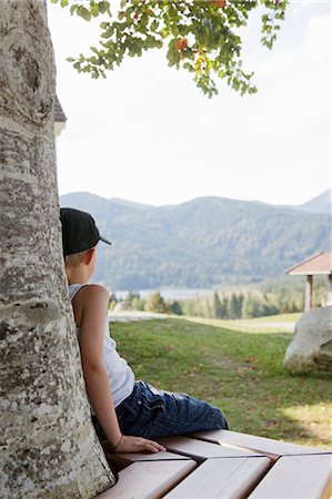 Boy sitting on bench against tree Stock Photo - Premium Royalty-Free, Code: 649-05802121