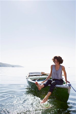 Woman dangling feet from boat in lake Stock Photo - Premium Royalty-Free, Code: 649-05819838