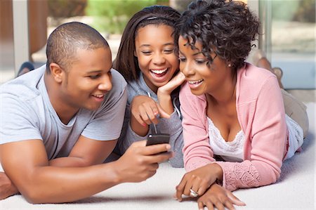 Famille souriante ensemble à l'aide de téléphone portable Photographie de stock - Premium Libres de Droits, Code: 649-05819974