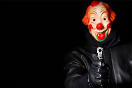 simsearch:649-06113680,k - Man in clown mask pointing gun Fotografie stock - Premium Royalty-Free, Codice: 649-05820028