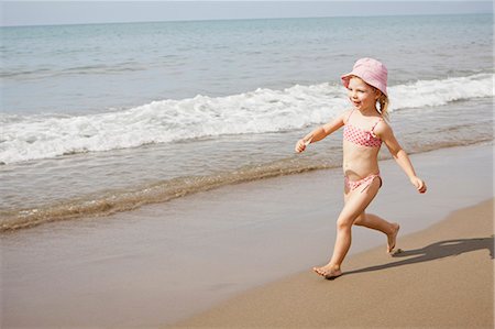 Girl in sunhat running on beach Stock Photo - Premium Royalty-Free, Code: 649-05820248