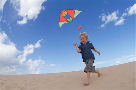 Boy flying kite on sand dune Stock Photo - Premium Royalty-Free, Code: 649-05820295