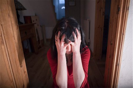 frighten - Woman clutching her head in doorway Stock Photo - Premium Royalty-Free, Code: 649-05820643