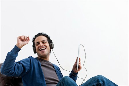 excited happy tablet - Man in headphones dancing in chair Stock Photo - Premium Royalty-Free, Code: 649-05820799