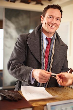 recepção - Businessman paying at hotel front desk Foto de stock - Royalty Free Premium, Número: 649-05820956