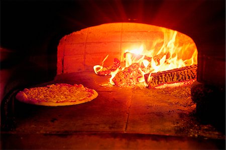 sepia toned - Pizza baking in wood burning oven Stock Photo - Premium Royalty-Free, Code: 649-05821475