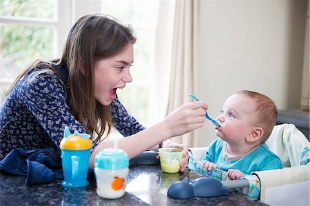 Girl feeding baby brother at table Foto de stock - Sin royalties Premium, Código: 649-05949523