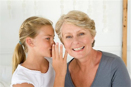 Girl whispering to grandmother Foto de stock - Royalty Free Premium, Número: 649-05949664