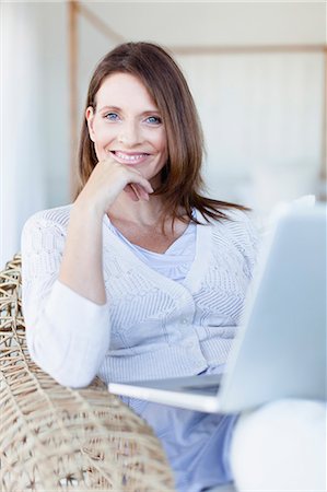 Woman using laptop in armchair Stock Photo - Premium Royalty-Free, Code: 649-05949921