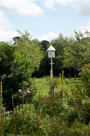 spring garden vertical nobody - White birdhouse in lush garden Stock Photo - Premium Royalty-Free, Code: 649-05950459