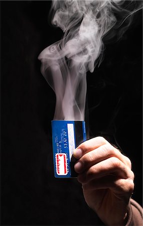 Hand holding smoking credit card Stock Photo - Premium Royalty-Free, Code: 649-05950604