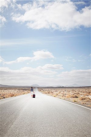 suitcase walking away - Woman rolling luggage on rural road Stock Photo - Premium Royalty-Free, Code: 649-05950792